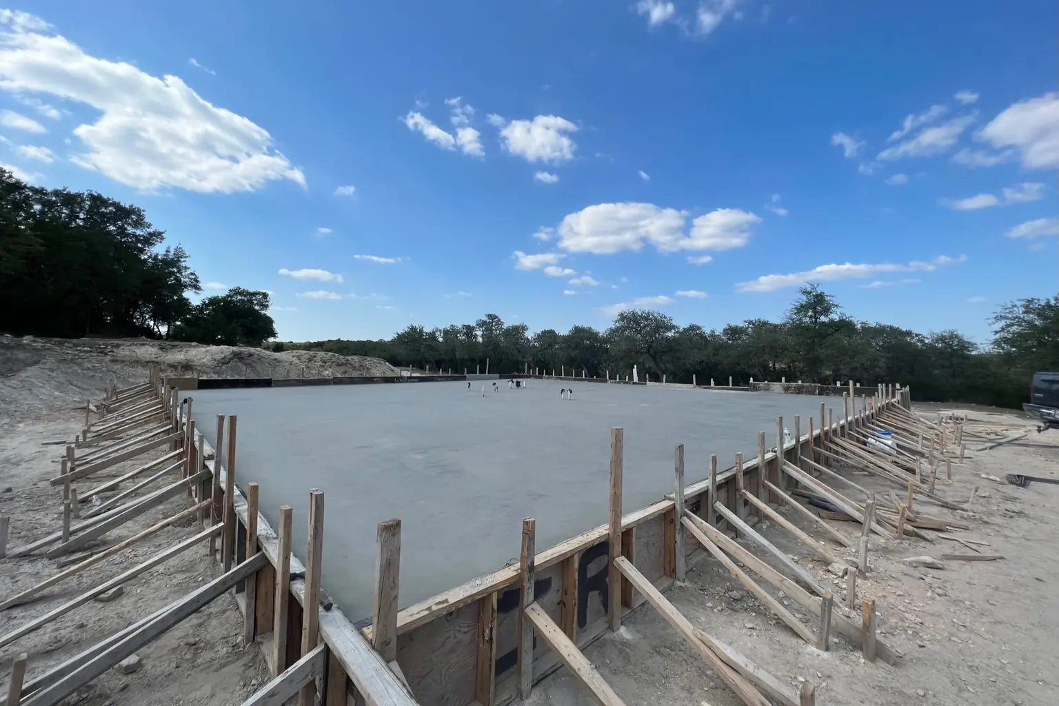 Freshly poured concrete foundation slab with wood forms and bracing, representing commercial construction in Seguin, TX